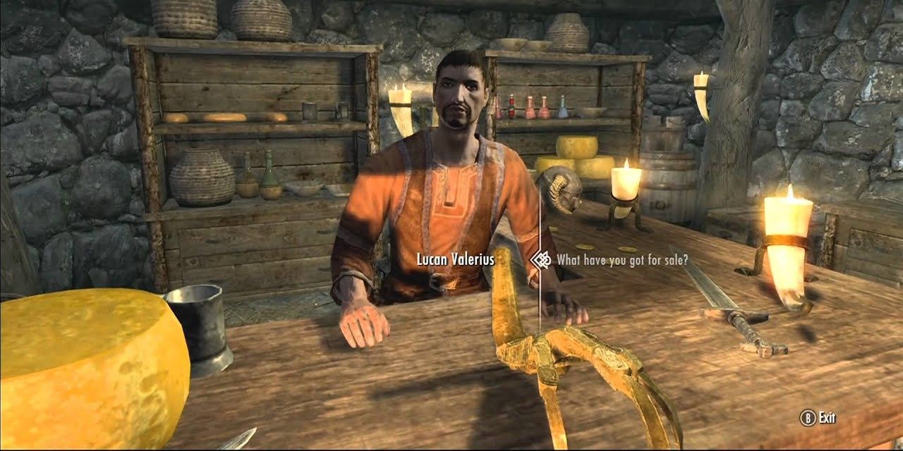 A screenshot of Lucas Valerian in his general store. The golden claw item is on the table, as well as a wheel of cheese, a sword, and several candles. The dialogue prompt reads &quot;What have you got for sale?&quot;