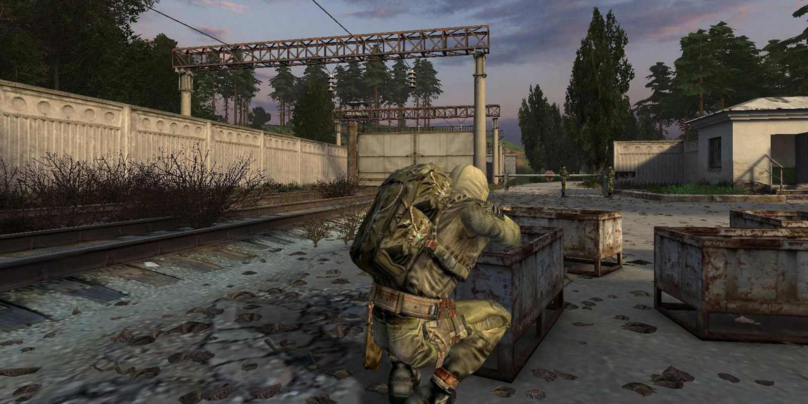 a wide shot of a soldier crouched behind boxes in an industrial area from Stalker Shadow Of Chernobyl