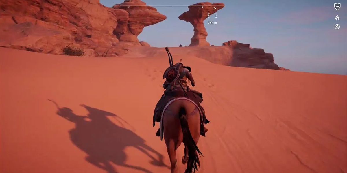 AC Origins a player riding up a sandy dune on horseback