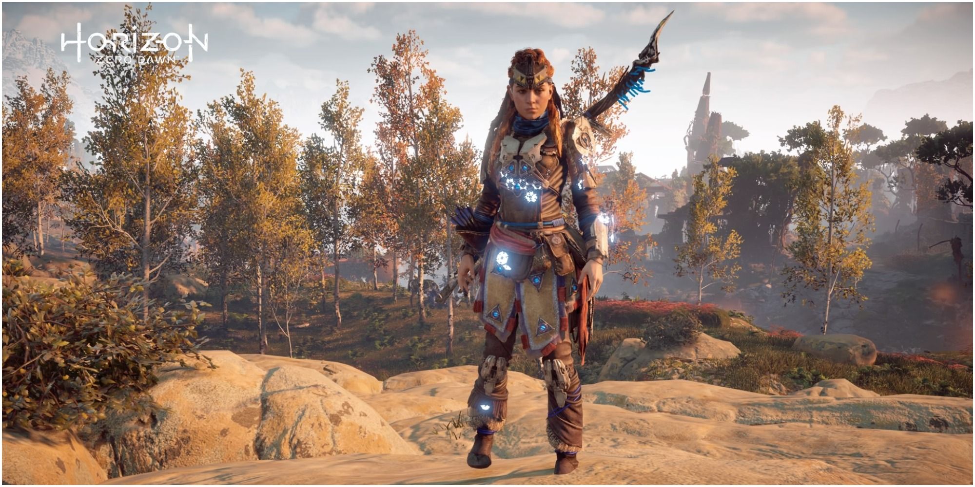 Aloy standing on rocks in armor with trees behind her