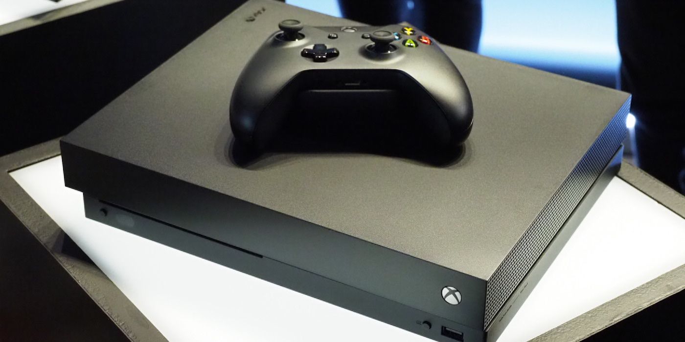 Xbox One X with controller on top of it.