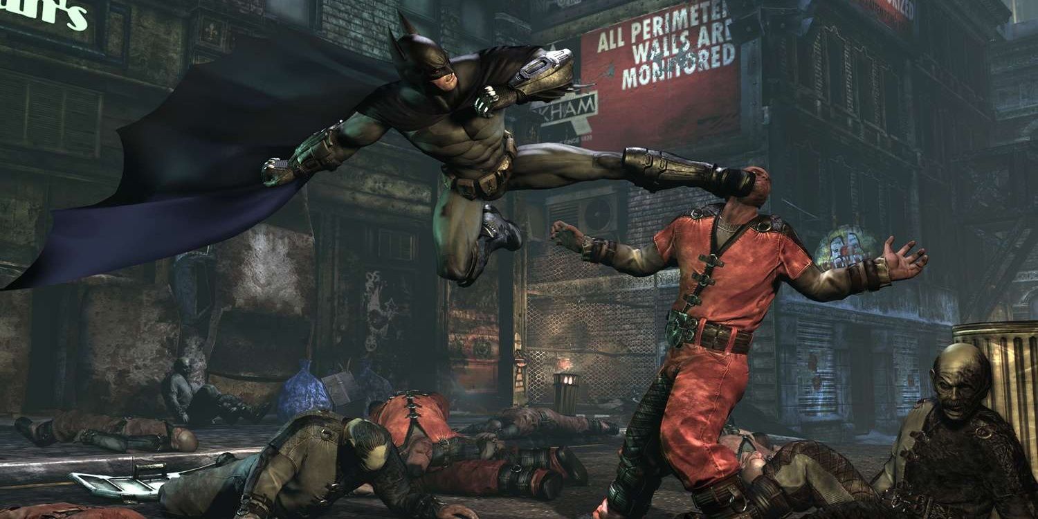 Batman lands a jumping kick right in the face of a prisoner in Arkham City.