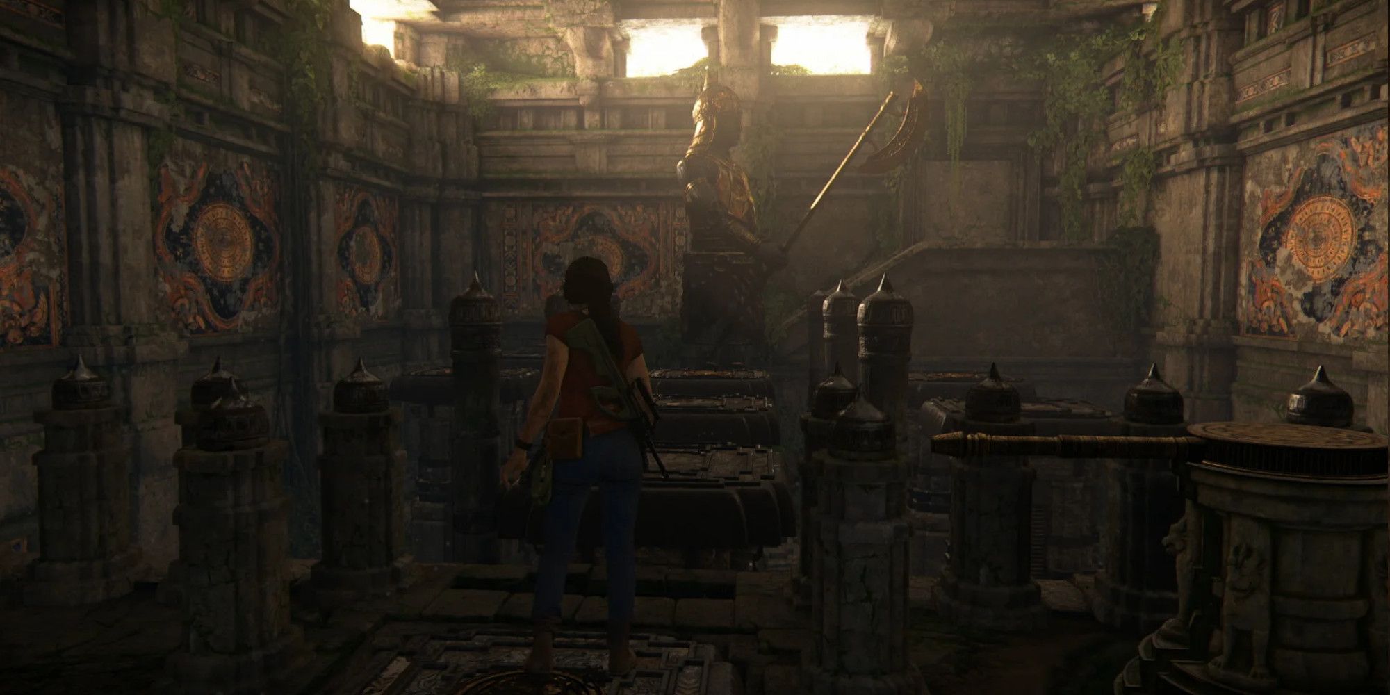chloe stands on a platform in a room with a large statue holding a long axe