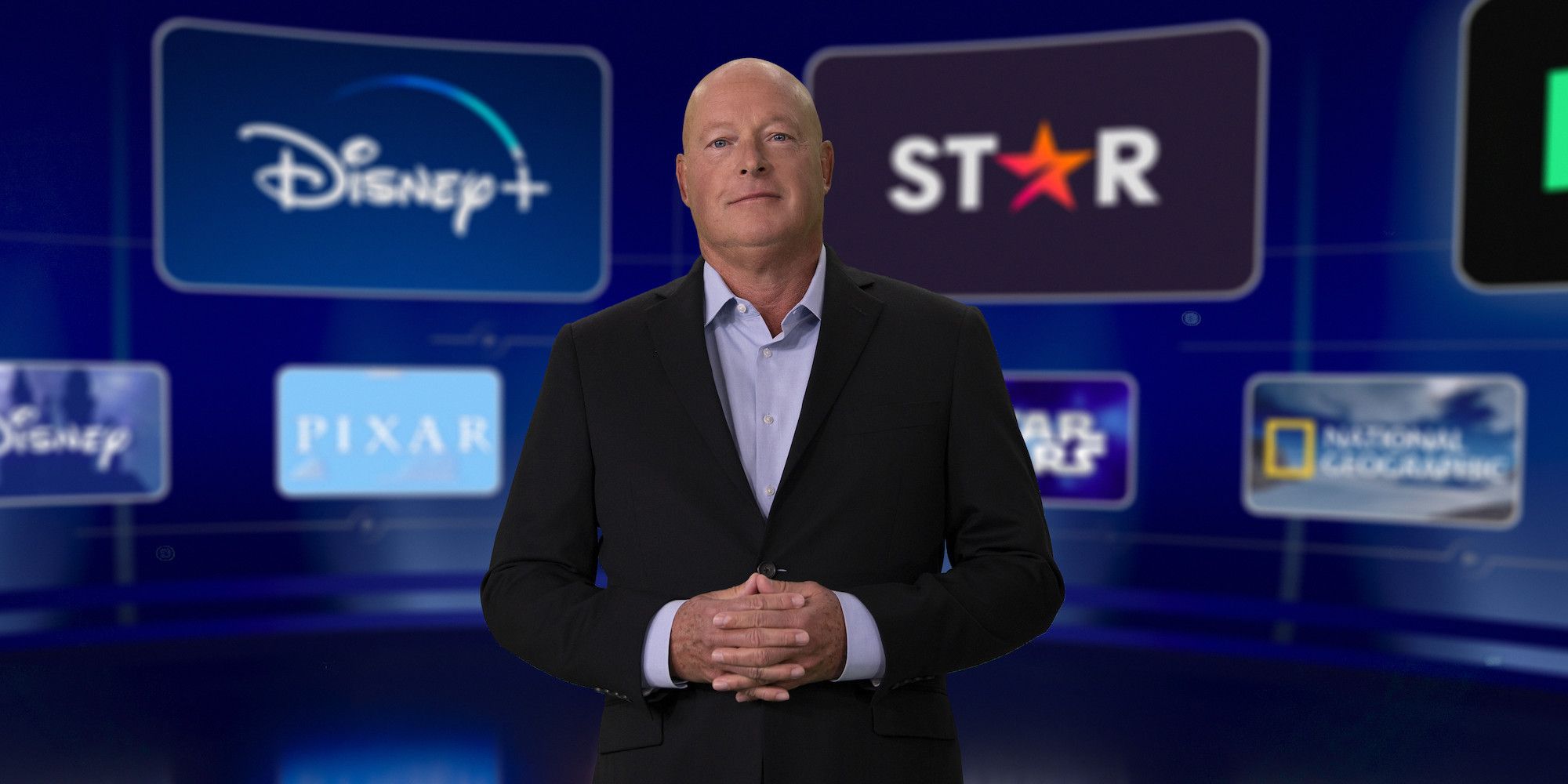 Disney ceo bob chapek in front of the disney plus and star logos