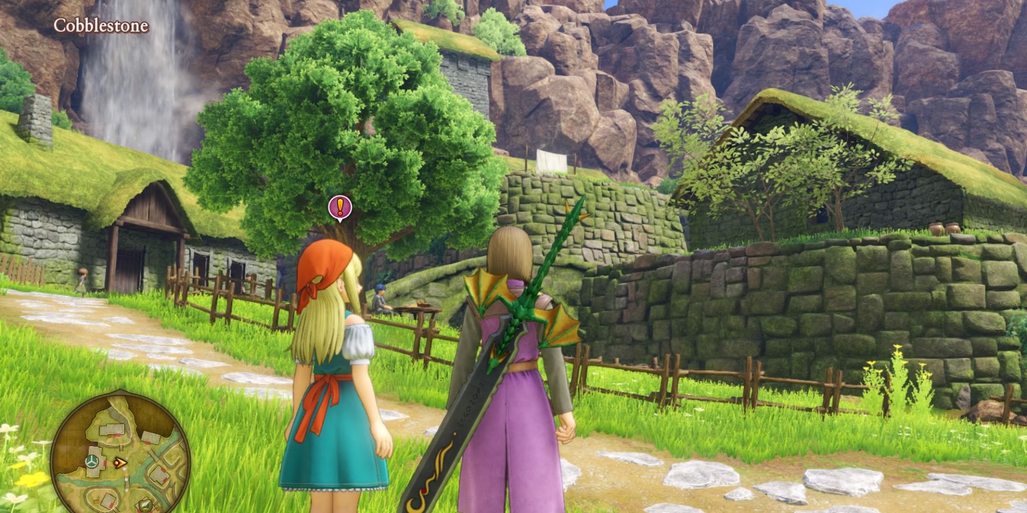 Dragon Quest Gemma and the Hero, surrounded by grass and a stone path, are stood near cobblestone walls and thatched roofed houses