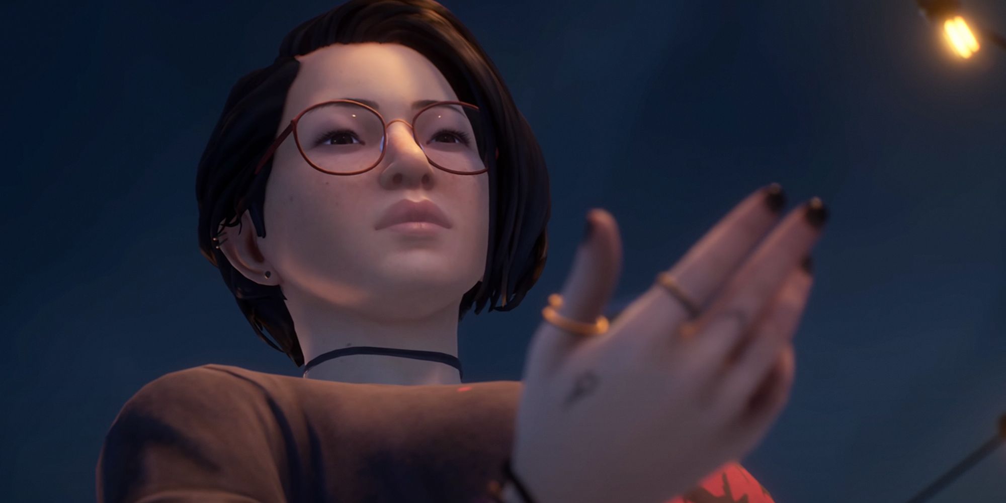 Alex Chen from Life Is Strange: True Colors looking in contemplation at her hand.