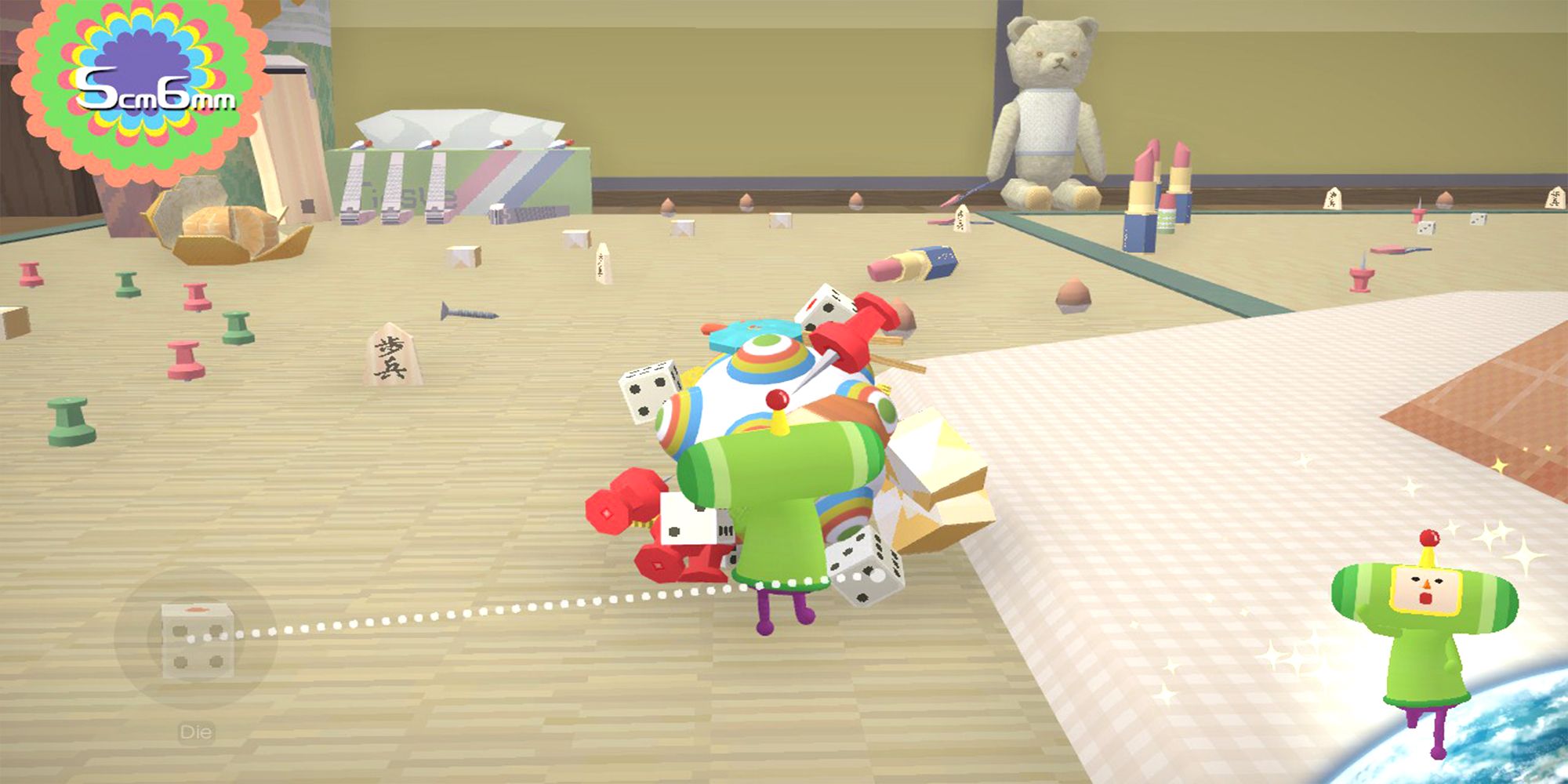 The first level of Katamari, showing the small green protagonist Prince, rolling up small objects such as dice and safety pins on a wooden floor.