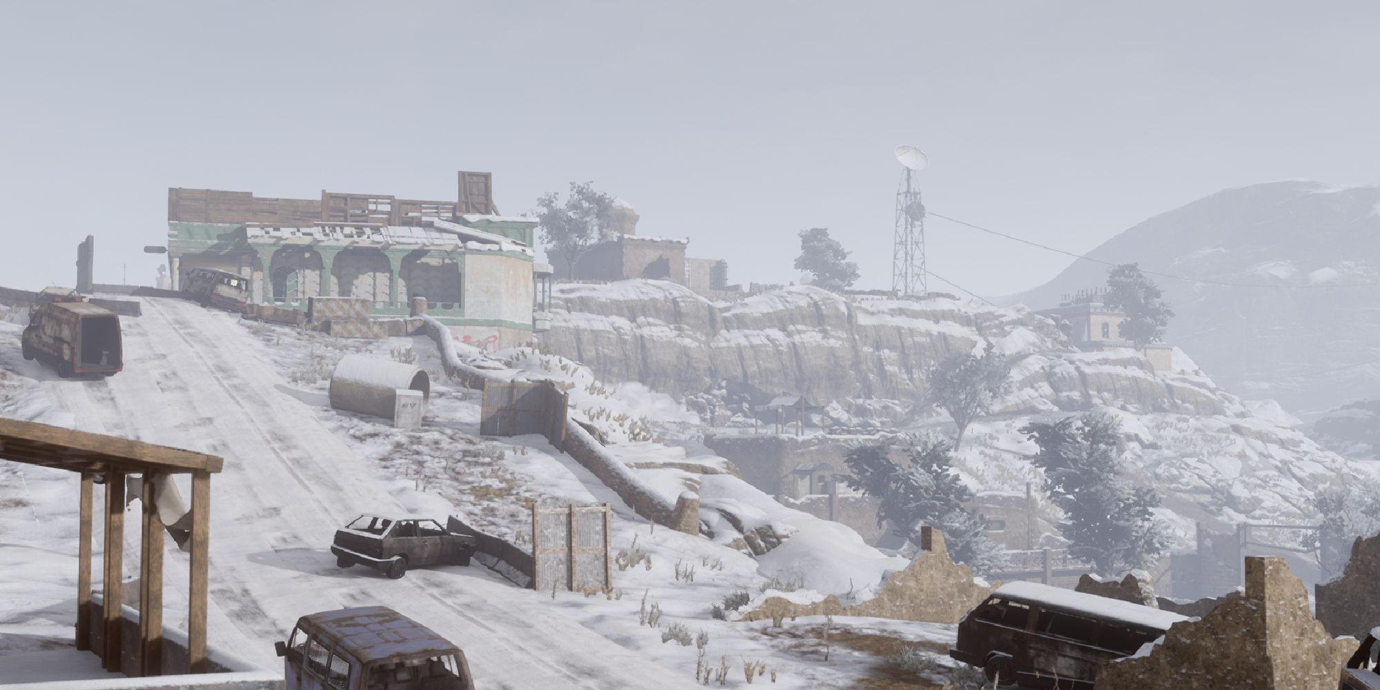 Insurgency Sandstorm Maps a wide shot of the map Hillside with a steep incline leading up to a building on top of a snow-covered cliff with cars and ruined buildings lining the incline