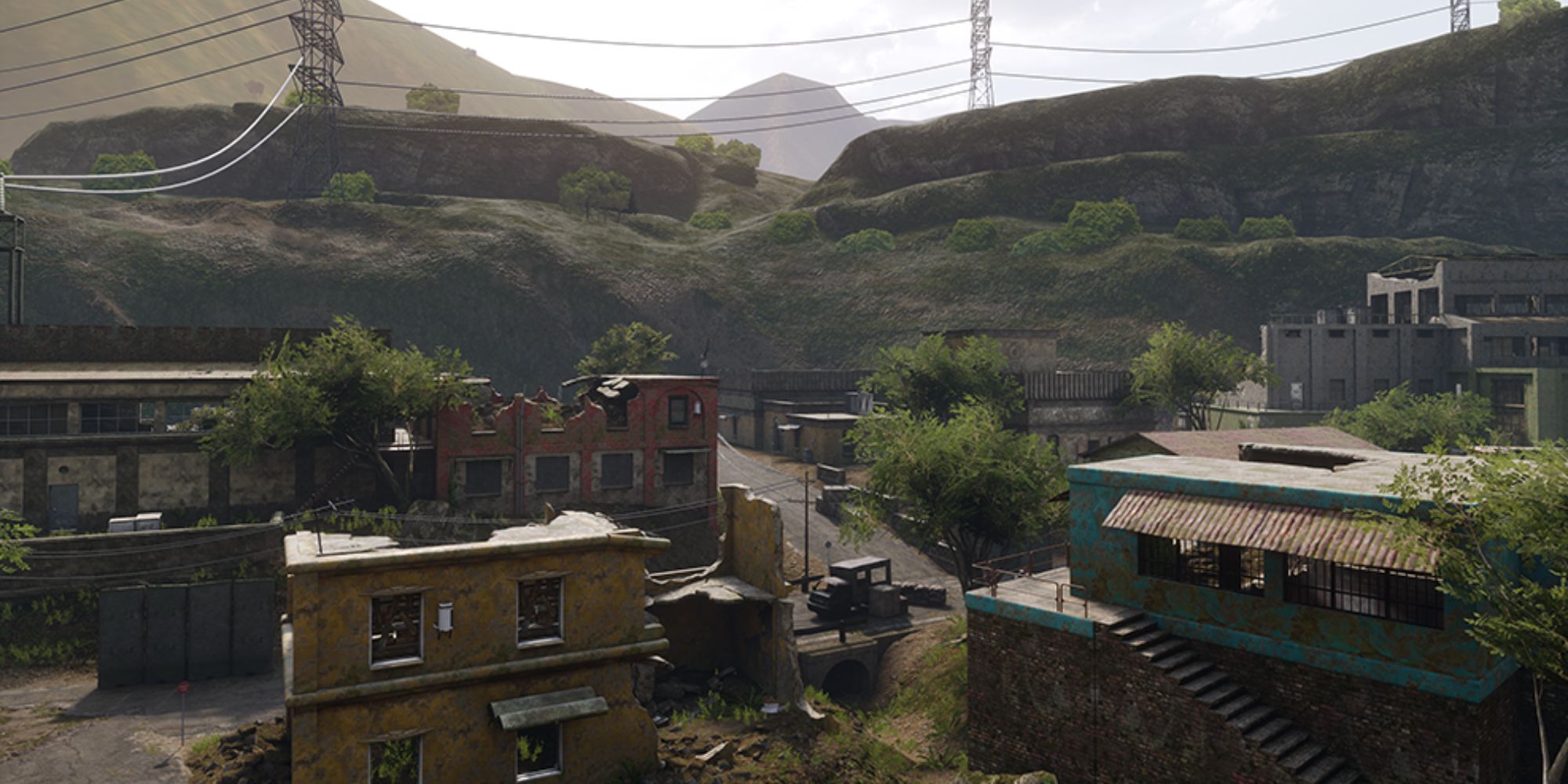 Insurgency Sandstorm Maps a wide shot of the map Power Plant with colourful ruined buildings in the foreground surrounded by green trees with towering transmission towers in the distance