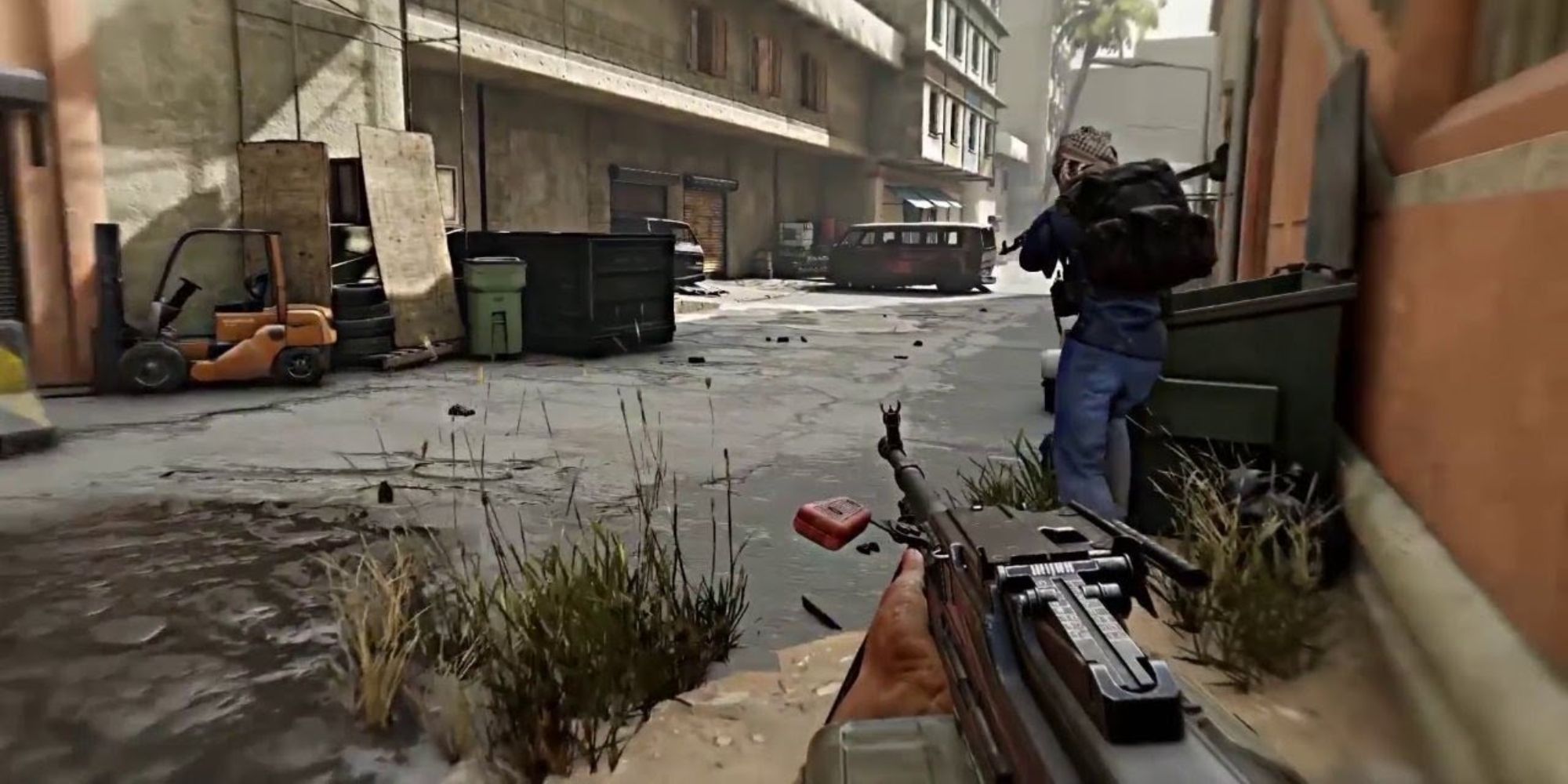 Insurgency Sandstorm Maps a first-person perspective view of an LMG with a soldier running away in the distance against a wall of grey buildings in the background