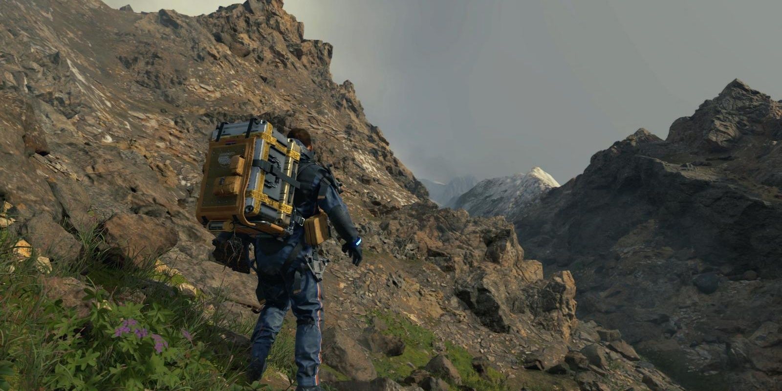 Sam stands on the side of a mountain in Death Stranding 