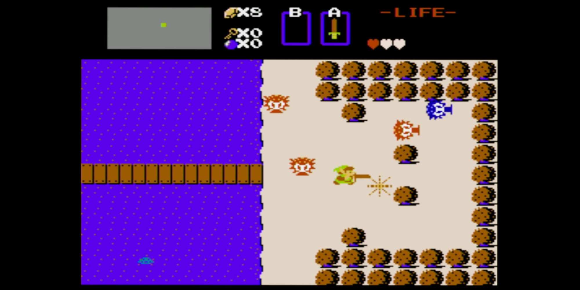 Best Overworlds a screenshot of gameplay from the original The Legend Of Zelda game with Link fighting enemies on a beach near water and a long wooden bridge