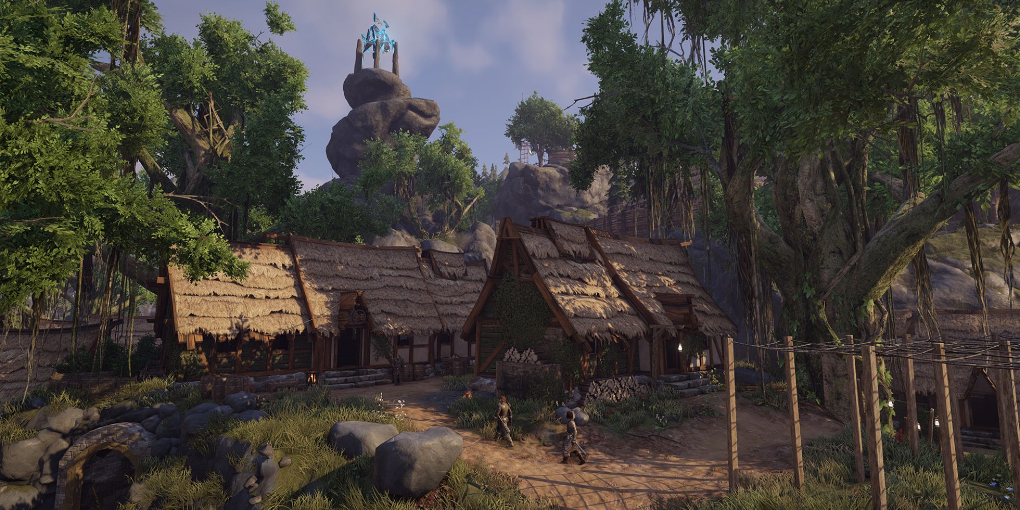 Elex a wide shot of a medieval style village called Goliet with hatched roof homes surrounded by lush green trees with a tower in the distance 