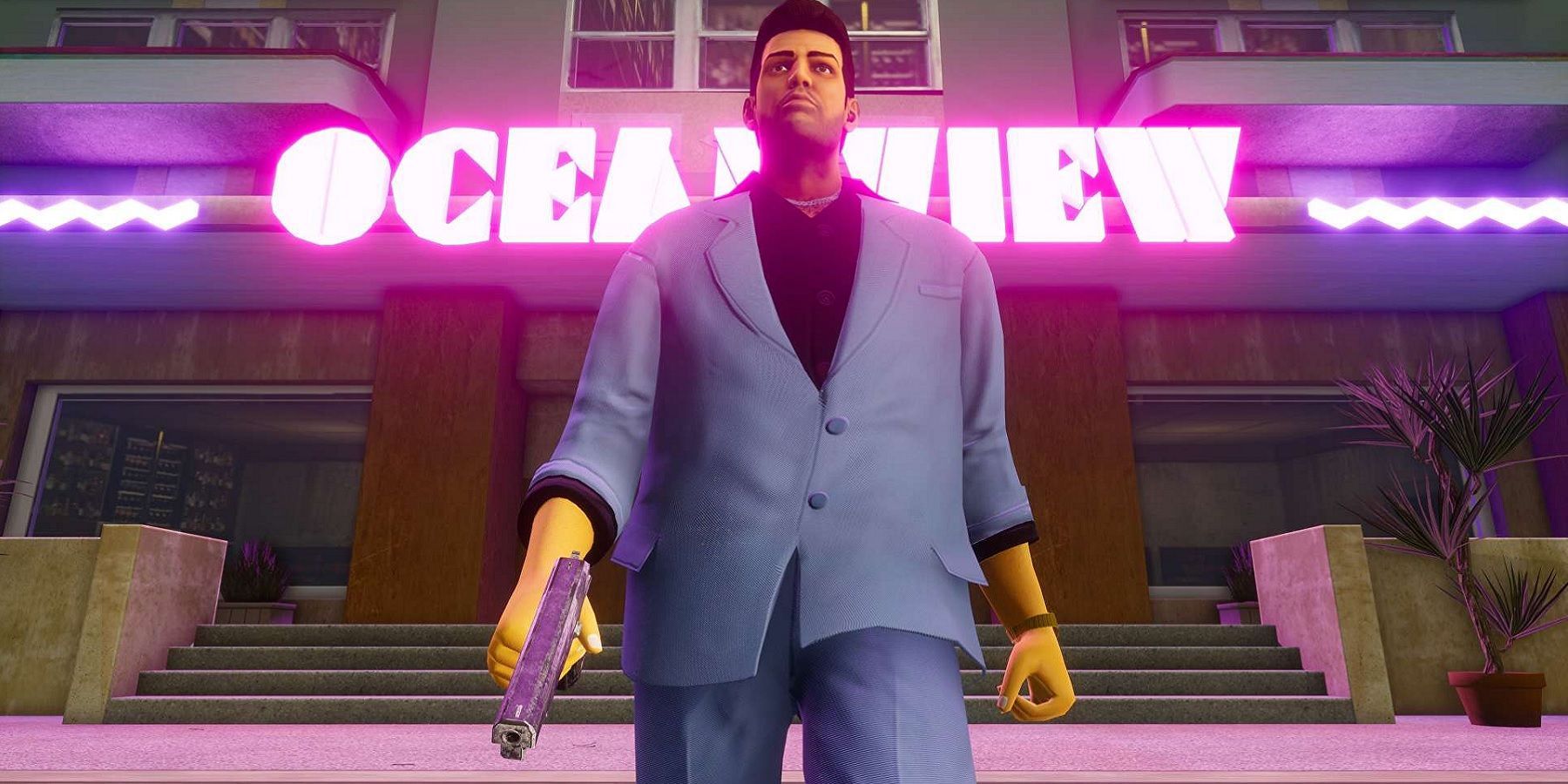 Tommy walks in front of the Ocean View hotel in the Vice City remaster, suited up and with a pistol