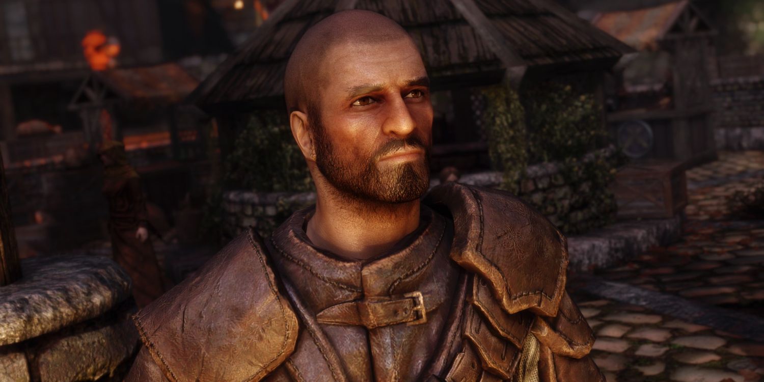 A bald man in leather armor looks pensively out out shot at a stone market during dusk.