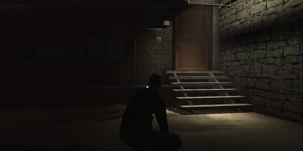 Splinter Cell, Sam crouches in the shadows outside of a well-lit door