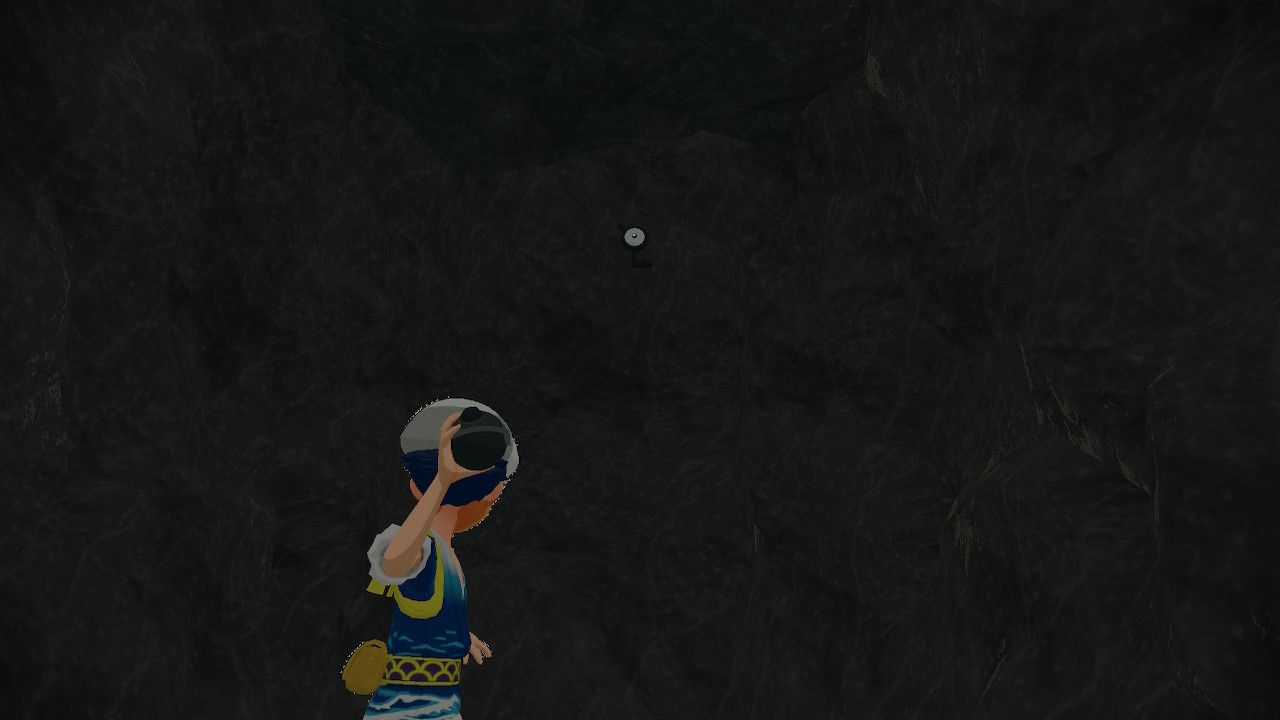 Pokemon Trainer aiming his pokeball at Unown L inside a cave, in Pokemon Legends Arceus.