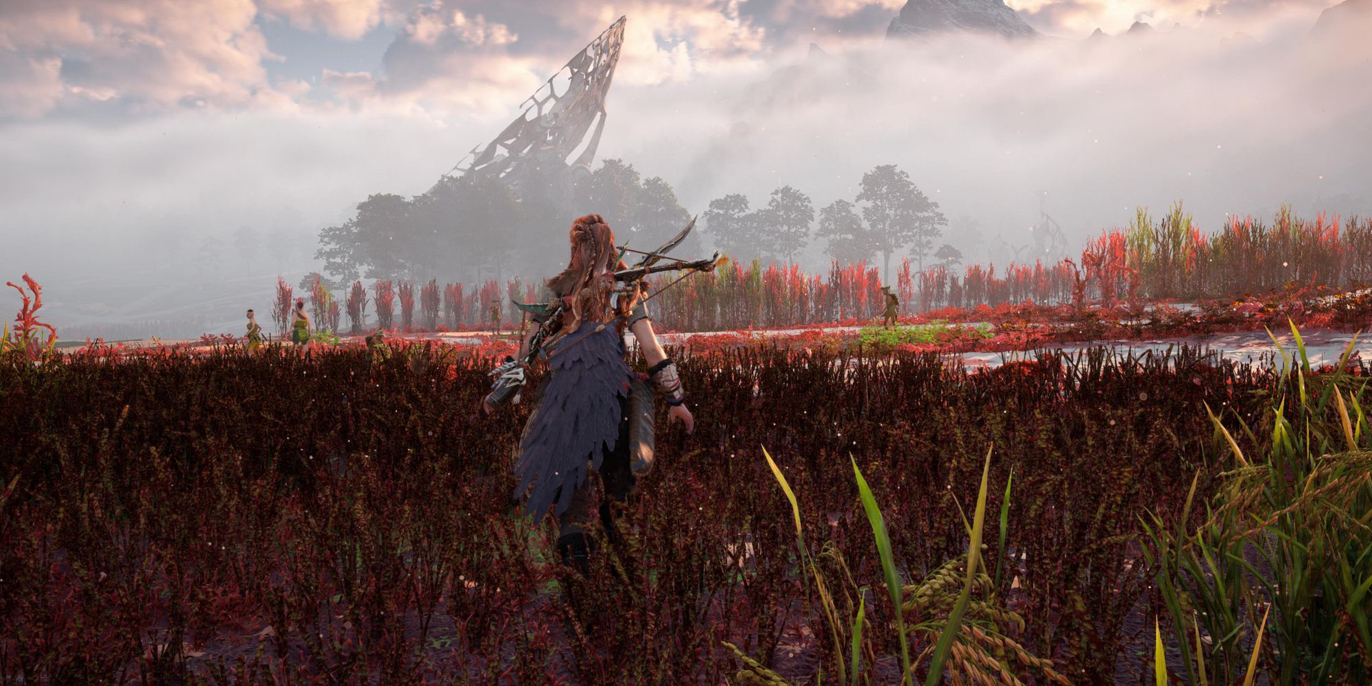 Horizon: Forbidden West, Aloy walking through the red grass with a tall structure in the distance.