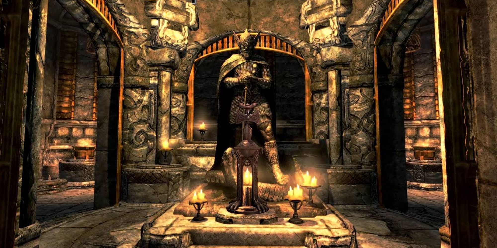 A statue of a god stands in the middle of a stone chamber, lit up with candles.