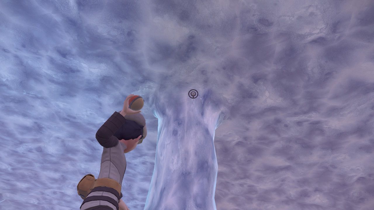 Pokemon Trainer aiming his pokeball at Unown O inside an ice cave, in Pokemon Legends Arceus.