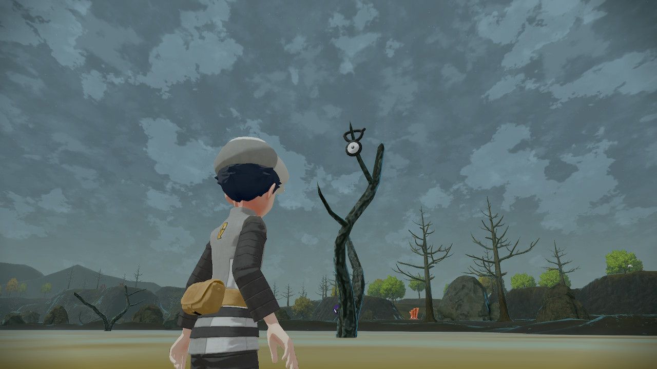 Pokemon Trainer looking at Unown V sitting on a dead tree, in Pokemon Legends Arceus.