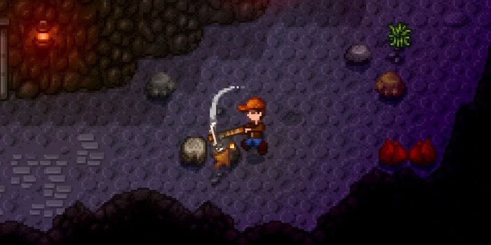 An overhead shot of a capped person mining a boulder in a dark cave.