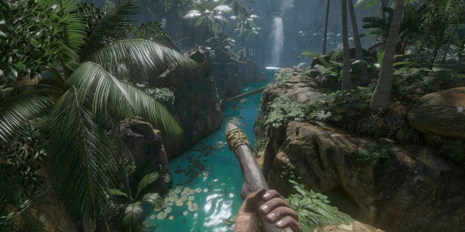 A spear-wielding character stands by the banks of Green Hell's bright blue river and the surrounding foliage.