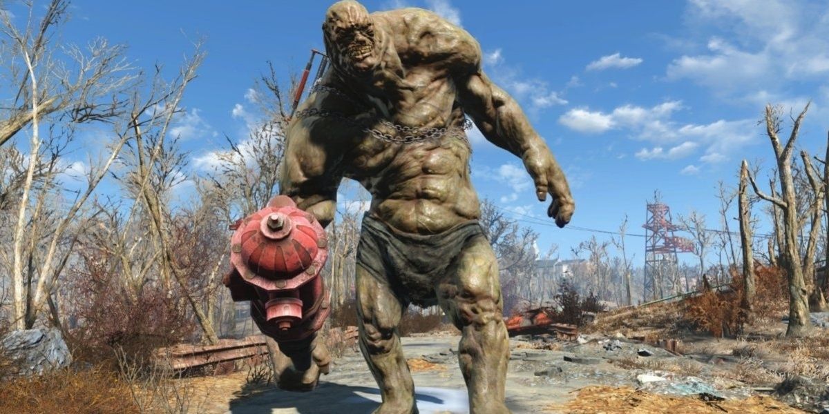 A Super Mutant Behemoth from Fallout 4 lumbers across a rocky, destroyed road.