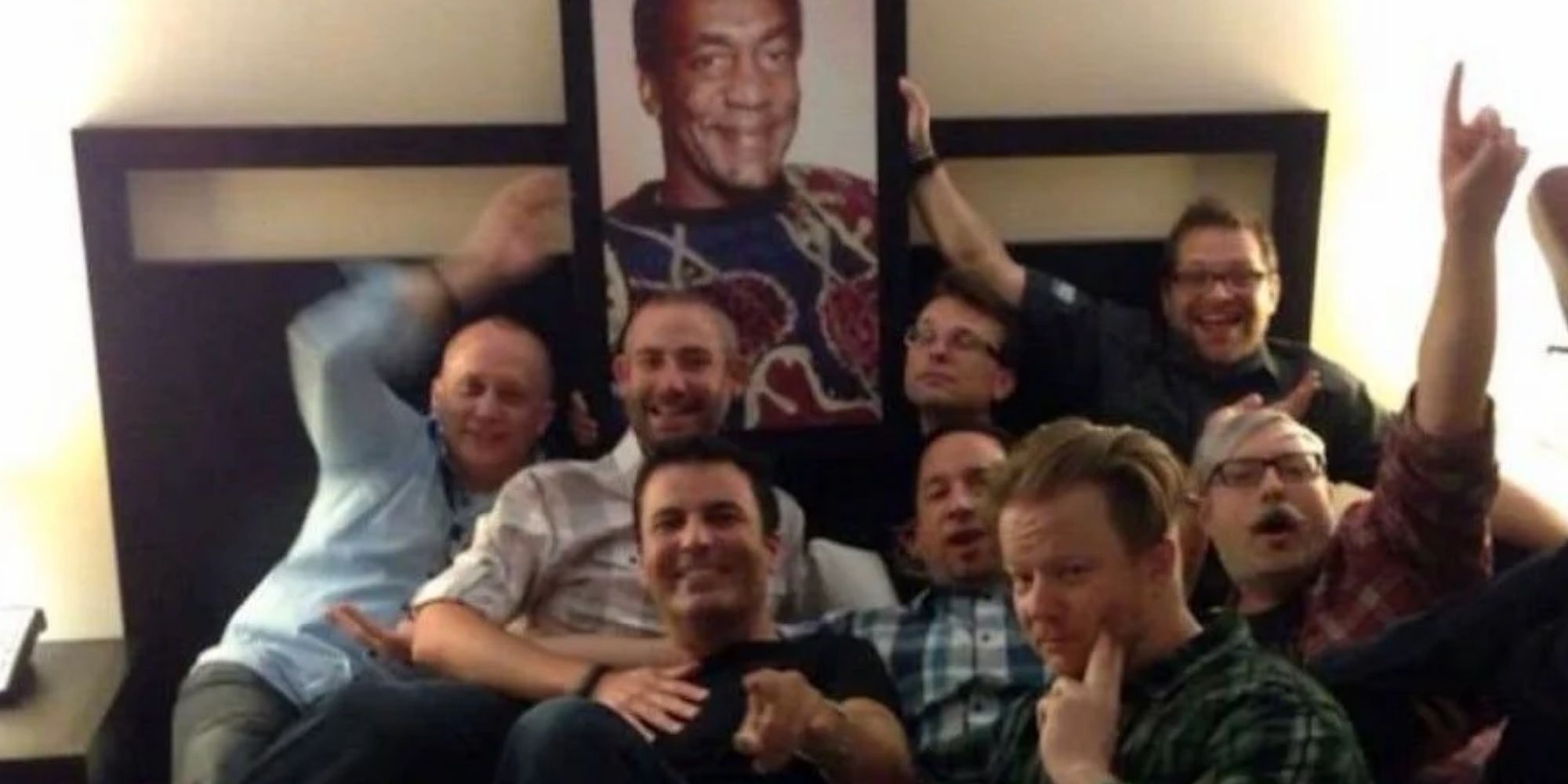 Male employees from Blizzard in front of a photo of Bill Cosby