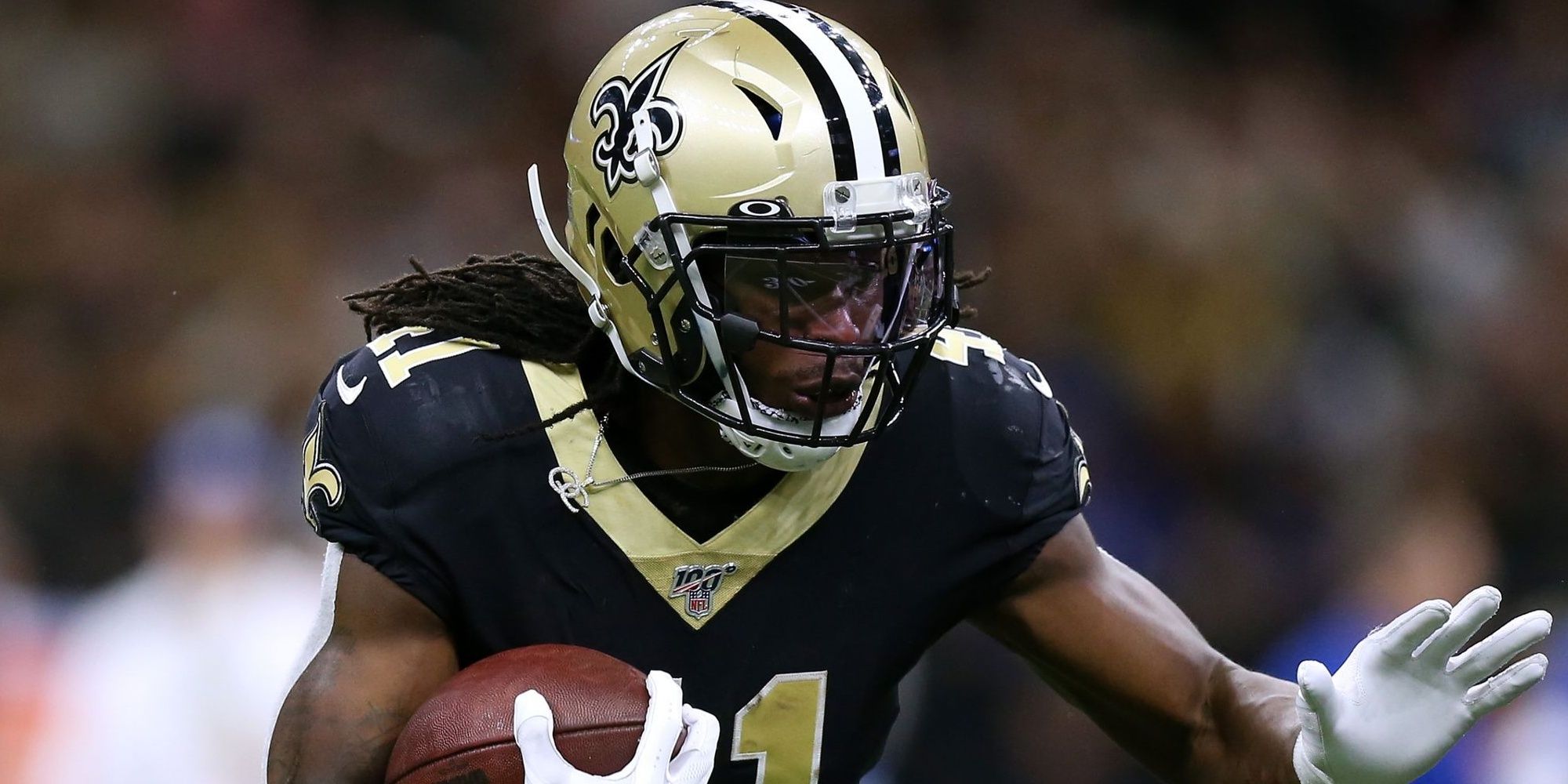 Alvin Kamara running the ball in Black and gold Saints jersey