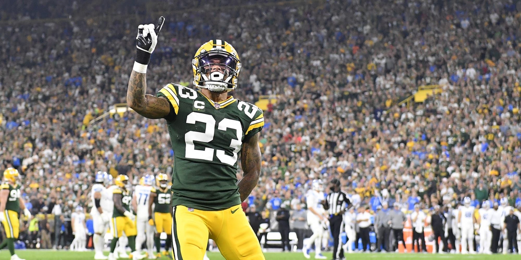 Jaire Alexander holding up a number 1 facing the crowd in a green and yellow Packers uniform