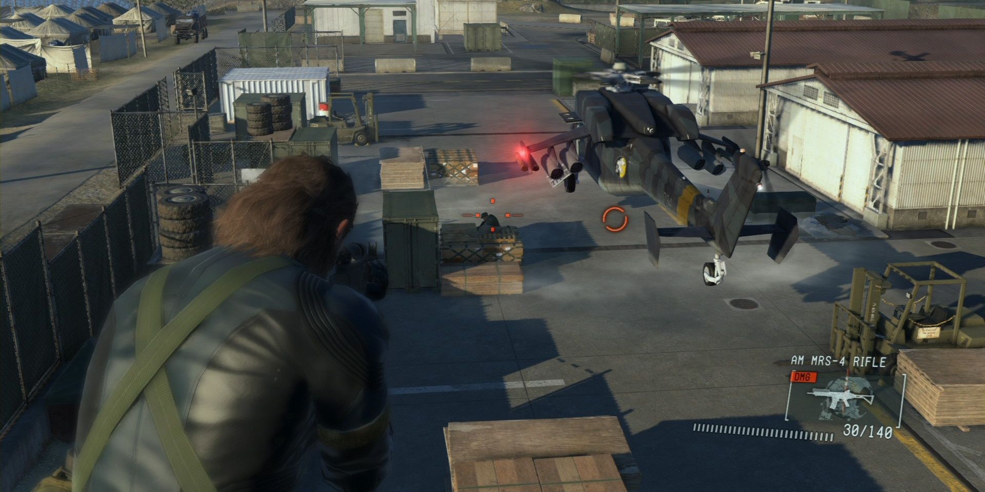 Snake aiming at a helicopter in a military camp in Metal Gear Solid V
