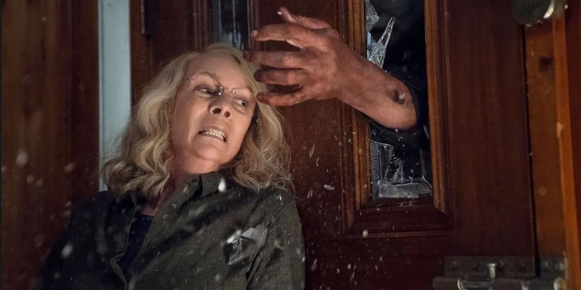 Laurie Strode gets ambushed by Michael Myers breaking in through a door in Halloween (2018).