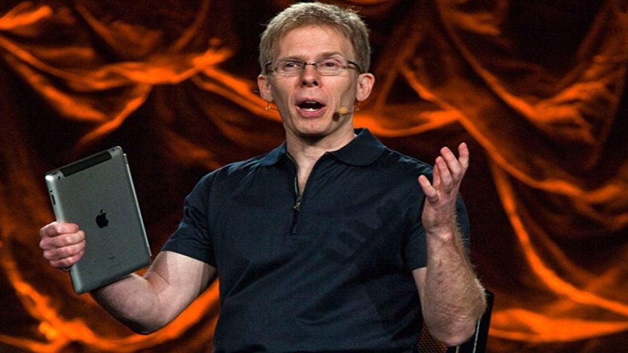 John Carmack holding his hands out at a conference holding an ipad