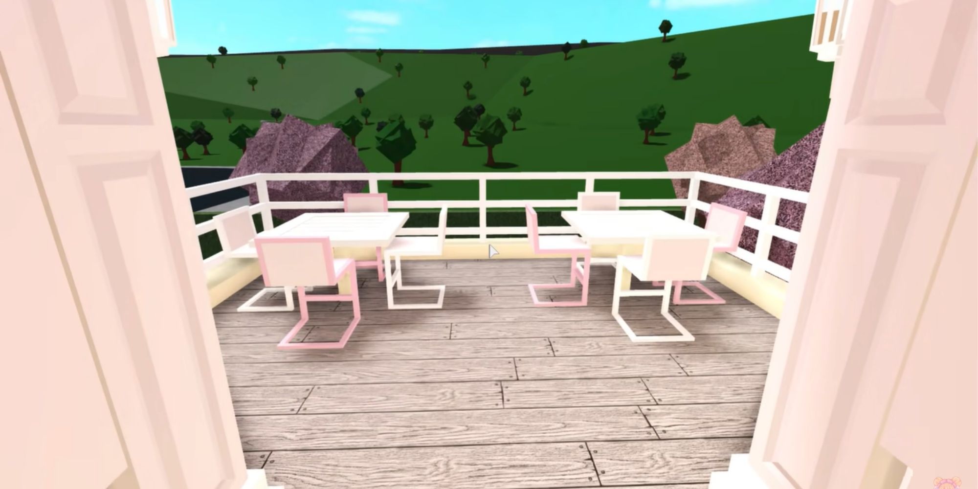 a cafe balcony with two tables overlooking a green hill landscape