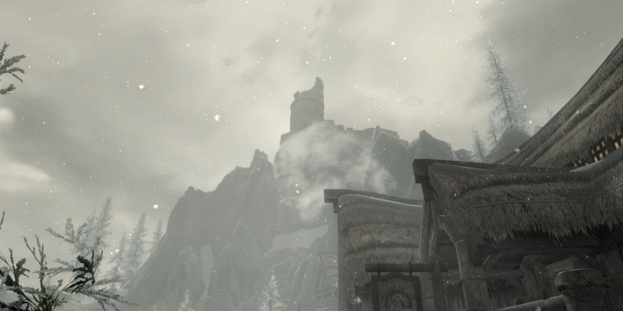 A shattered tower stands tall above a small town at the foot of a snowy mountain.