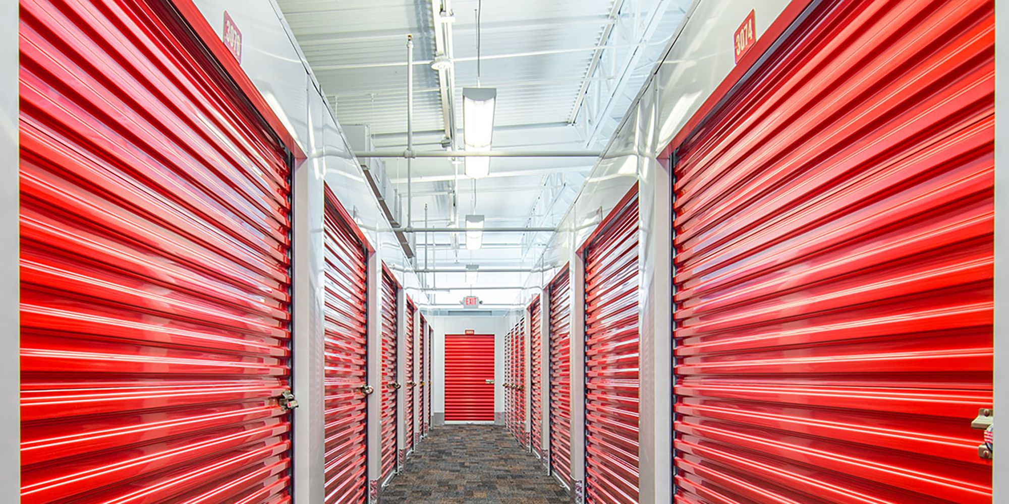 A hallway full of red-doored storage units inside of a CubeSmart location.