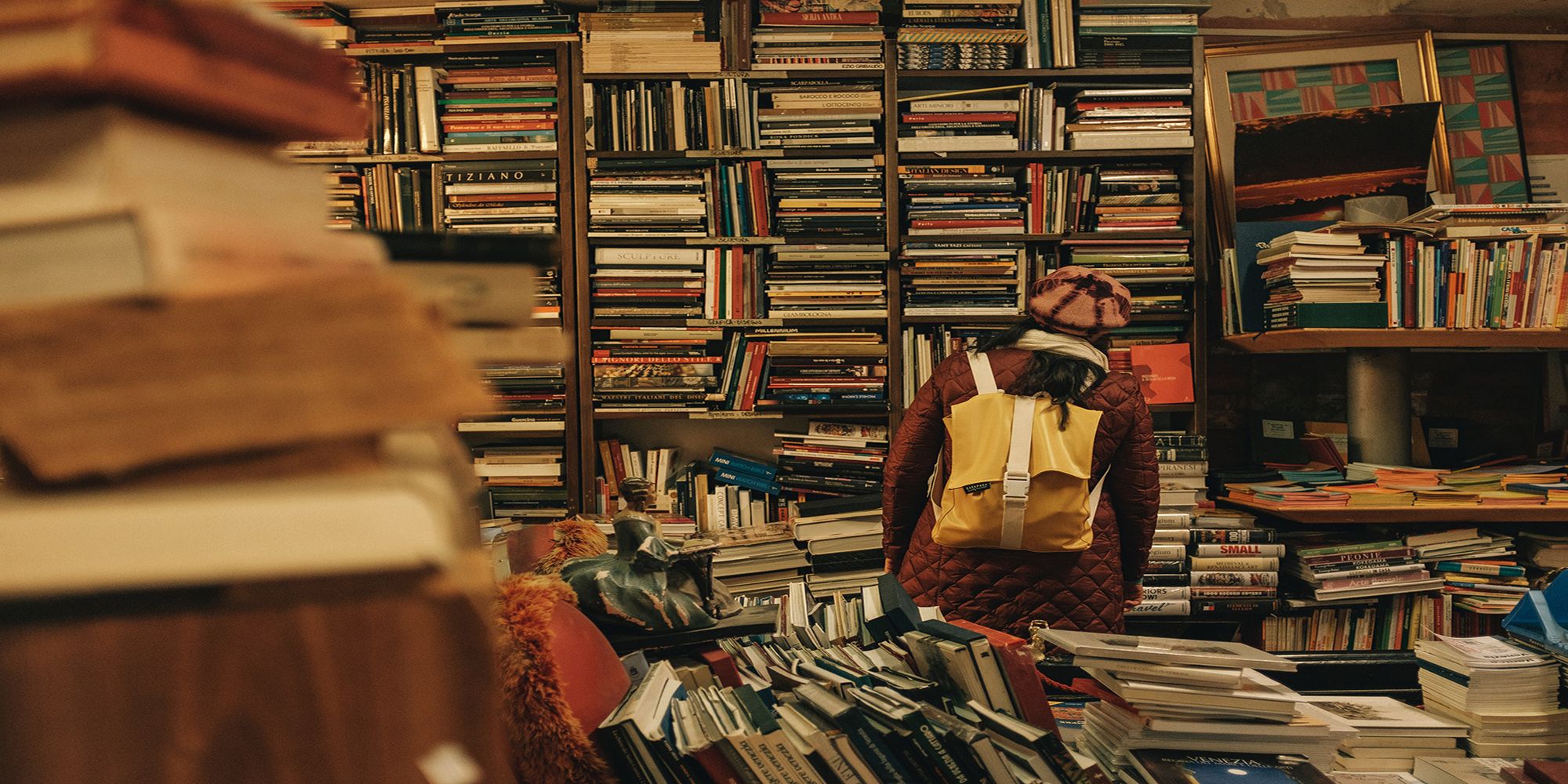 Woman looks through various shelves of a Venice, Italy library. Photo by Darwin Vegher via Unsplash.com.