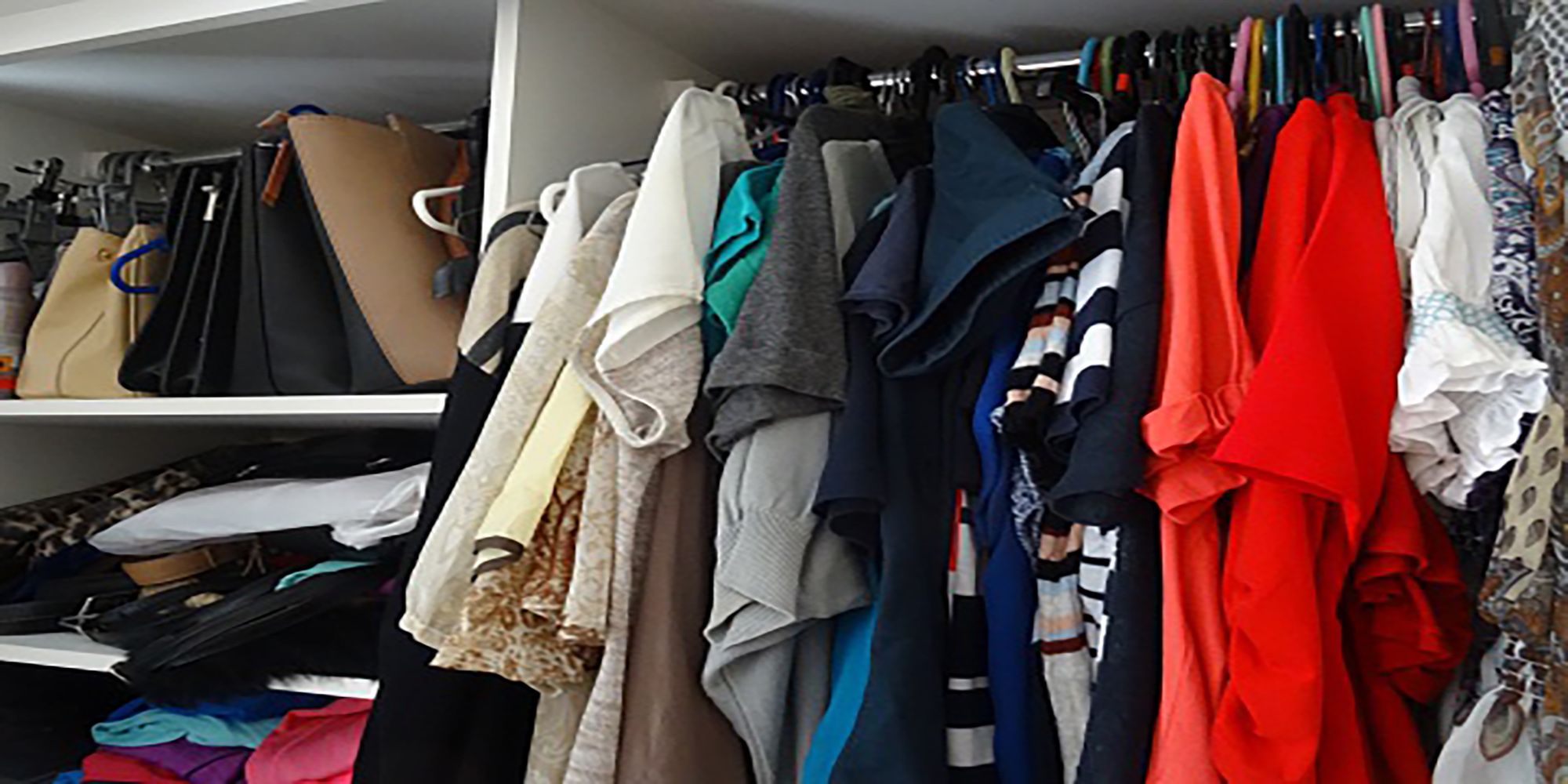 A photo of a closet filled with plenty of clothes, handbags, and other items.