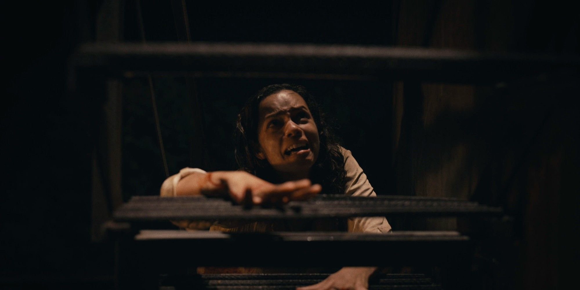 Georgina Campbell as Tess in Barbarian crawling up a staircase.