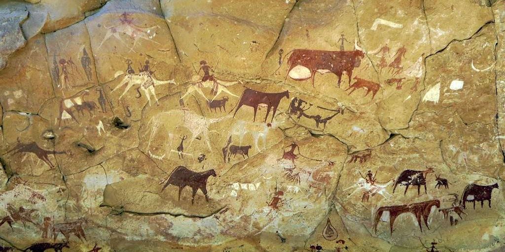 A cave painting depicting many people and animals
