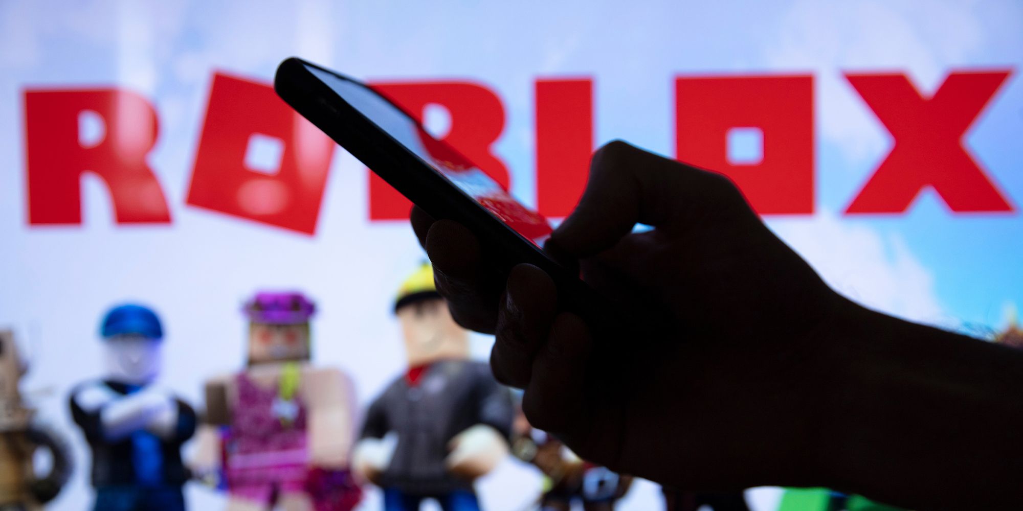 Roblox logo with a silhouetted hand holding a phone, it looks ominous