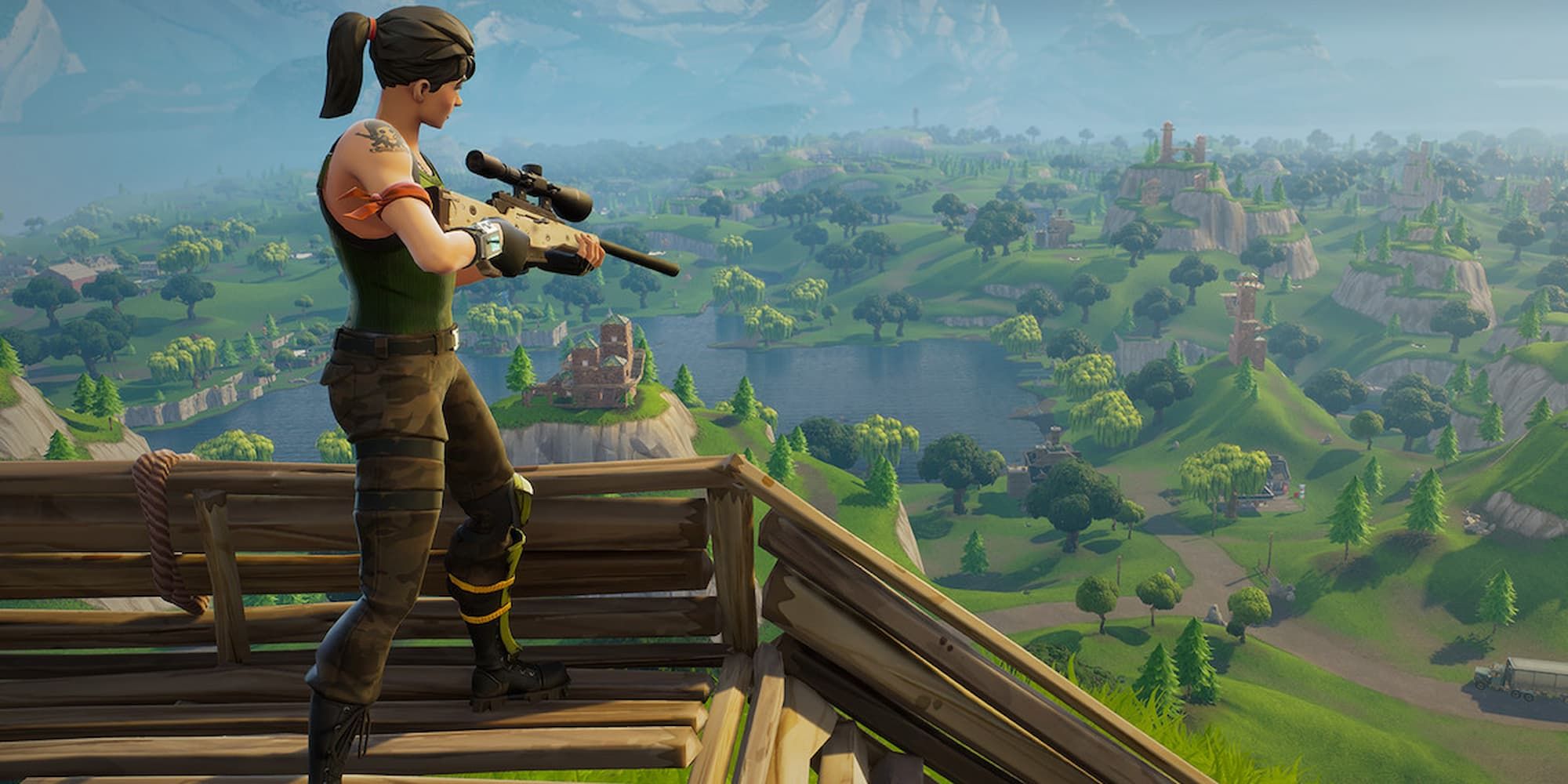A Fortnite default skin stands with a sniper rifle on top of a build, looking down to the island below.
