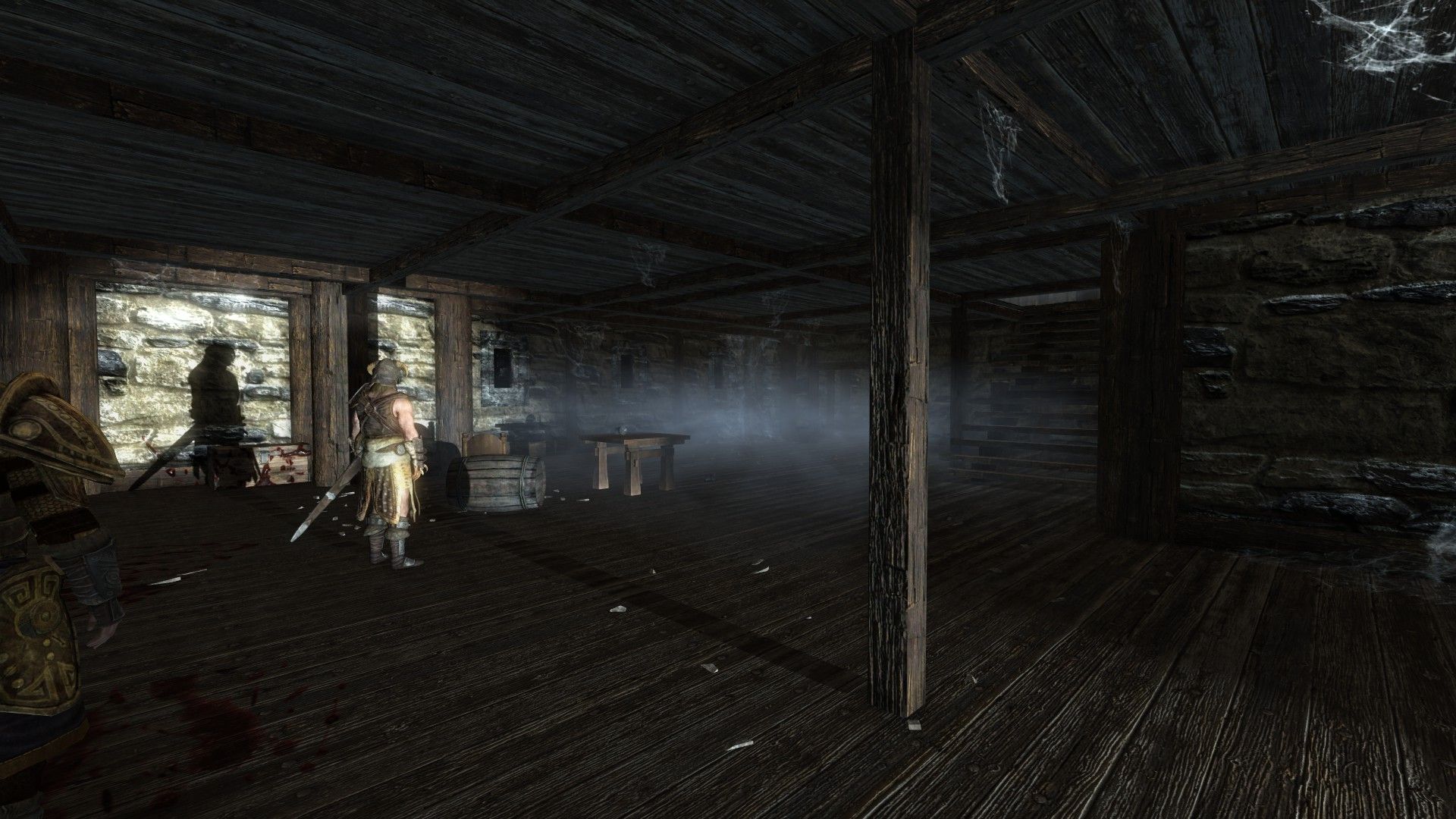 A man stands inside a starkly-lit house that has clearly been long abandoned.