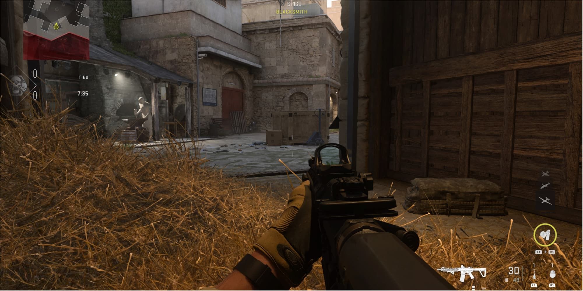 A camper goes prone in the hay at the stables of Al Bagra Fortress in Call of Duty: Modern Warfare 2