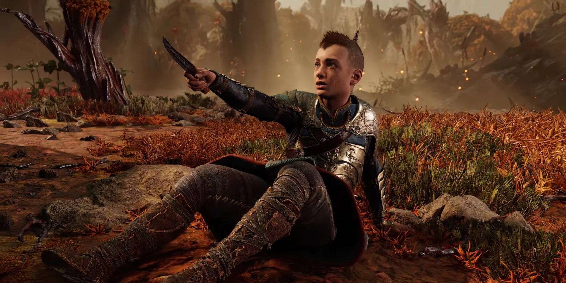 Screenshot of Atreus holding a knife at Angrboda on the ground during their first encounter in God of War Ragnarok. 