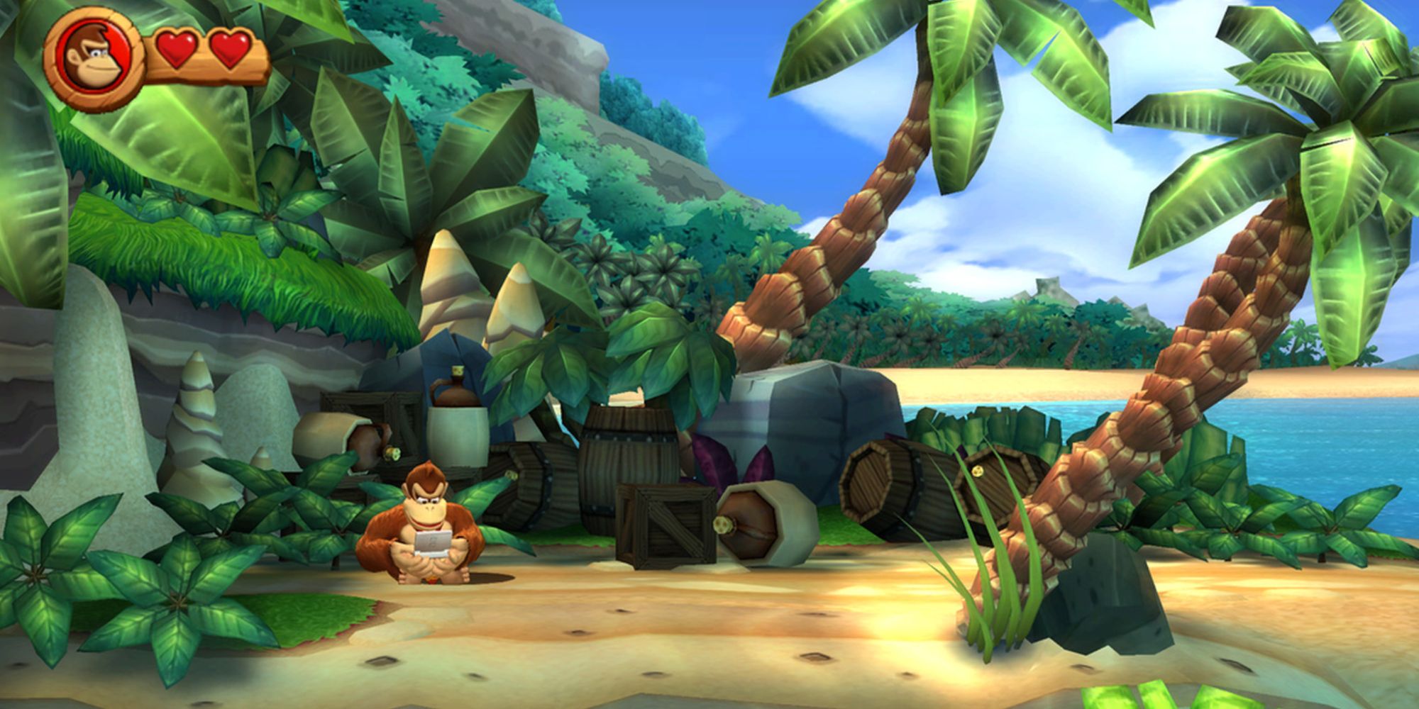 Donkey Kong sitting and playing a Nintendo 3DS on a sandy beach level in Donkey Kong Country Returns 3D