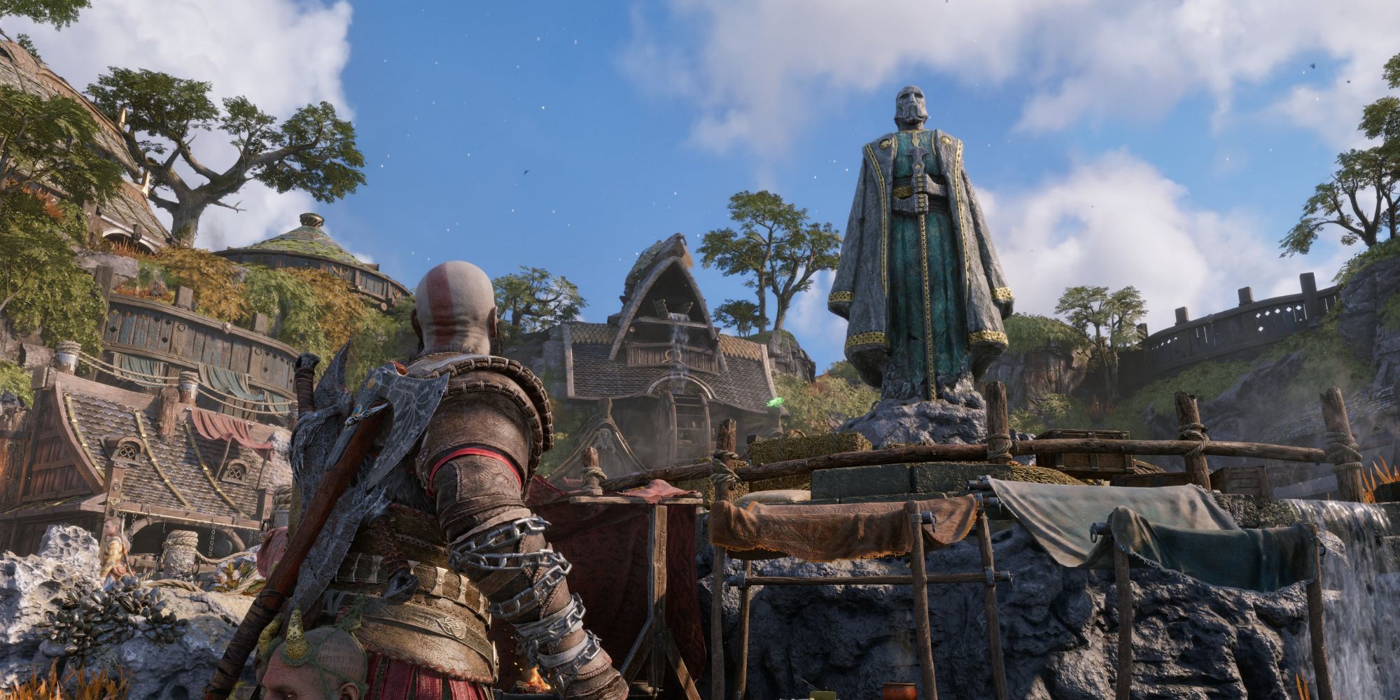 Kratos looking at a statue of Odin in God of War Ragnarok.