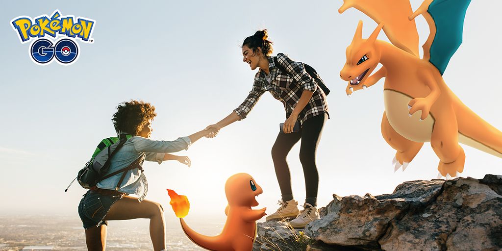 A person helping another person up a rock with Charmander and Charizard with them