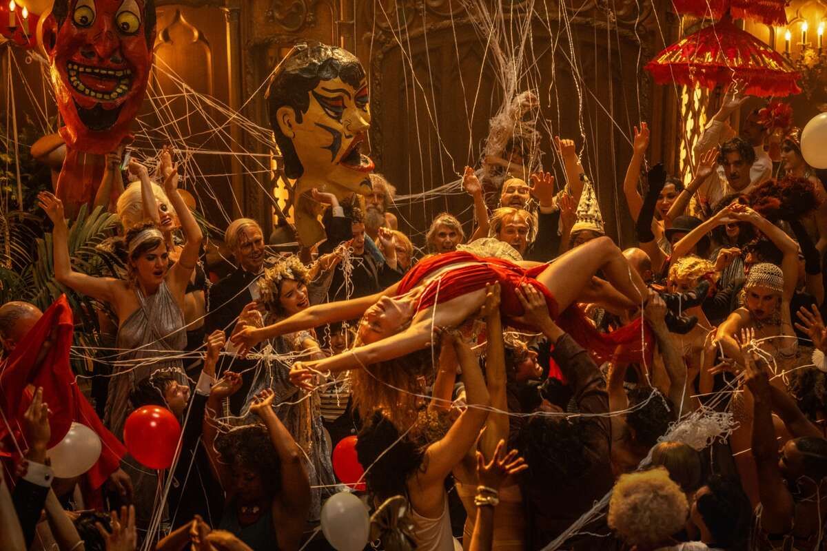 Margot Robbie being carried through a crowd covered in string during a party